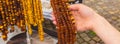 Hand of woman with shiny womanly amber necklaces on stall at the bazaar