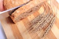 Hand of woman slicing fresh bread, ears of wheat Royalty Free Stock Photo