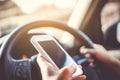 Hand of woman on steering wheel drive a car while using smartphone background