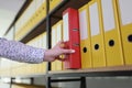 Hand of woman taking red ring binder from office archive Royalty Free Stock Photo