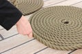 Hand of woman and thick rope wrapped in spiral lying on deck of ship