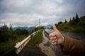 Hand of woman traveler with thumbs up on asphalt road go to travel Royalty Free Stock Photo