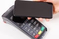 Hand of woman using payment terminal and smartphone to cashless paying. Finance concept