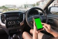 Hand of woman using smartphone with blank green screen monitor in SUV car Royalty Free Stock Photo