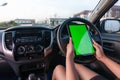 Hand of woman using tablet with blank green screen monitor in SUV car