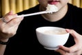 Hand of woman using white chopsticks holding hot steamed rice in white bowl Royalty Free Stock Photo