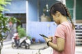 Hand of a woman wearing a watch and holding the phone plugged in headphones at the Bang Yai Park Background tree , Nonthaburi.