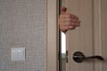 Hand of the woman who is behind the door, hold the door, opening or closing it. Royalty Free Stock Photo