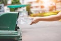 The hand of a woman who is dumping garbage in the trash.