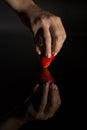 The hand of a woman who takes a strawberry and its reflection with black background Royalty Free Stock Photo