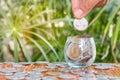 Hand of women putting coin In glass jar