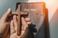 hand with wood cross over the bible on wood table with window light.christian backgound Royalty Free Stock Photo