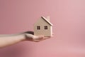 Hand with a wooden house resting on its palm.