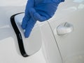 The hand of a worker in a blue glove closes the hatch of the gas tank of the car