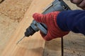 Hand of worker drills a hole with wooden plank using electric drill machine in workshop Royalty Free Stock Photo