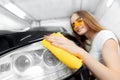 Hand worker girl polishes and clean microfiber headlights on black auto. Concept car wash service Royalty Free Stock Photo