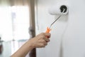 hand worker holding brush painting roller white on the wall house.