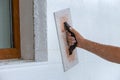 Hand of a worker with a tool for sanding and making smooth and even the surface of a house wall insulated with styrofoam