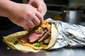 hand wrapping foil around a gyro for takeaway