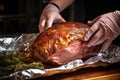 hand wrapping an oak-smoked lamb shoulder in aluminum foil