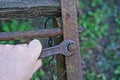 Hand with a wrench unscrewing a rusty nut