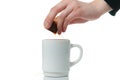 Hand wringing out tea bag in a mug on white