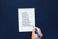 a hand writes in a notebook the words efficiency, quality, development on a blue background