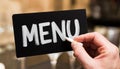 A hand writes the word menu on a black board with white chalk Royalty Free Stock Photo