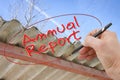 Hand writing Annual Report on a background image with an asbestos roof - concept image