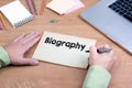 Hand writing Biography. Office desk with a laptop and stationery