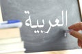 Hand writing on a blackboard in an Arabic class.