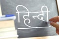 Hand writing on a blackboard in a Hindi class.