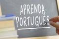 Hand writing on a blackboard in a Portuguese class.