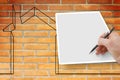 Hand writing on a blank sheet with a house outline against a brick wall - concept image with copy space Royalty Free Stock Photo