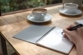 A hand writing down on a white blank notebook with coffee cup on wooden table Royalty Free Stock Photo