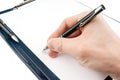 Hand writing on an empty document in a clipboard Royalty Free Stock Photo