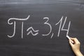 Hand writing the mathematical sign or symbol for Pi on a blackboard