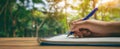 The hand writing in a notebook surrounded by nature's beautiful greenery..AI generated image Royalty Free Stock Photo