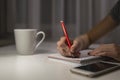 Hand writing notepad. office desk table, phone and coffee cup Royalty Free Stock Photo