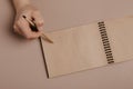 Hand writing in notepad using a pen, on gray background Royalty Free Stock Photo