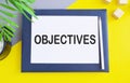 Hand writing Objectives to do list on white paper above Notebook, yellow background Royalty Free Stock Photo