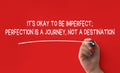 Hand writing It is okay to be imperfect affirmation on red cover background. Affirmation concept.