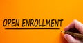 Hand writing `open enrollment`, isolated on beautiful orange background. Concept. Copy space Royalty Free Stock Photo