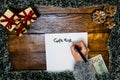 Hand writing on paper Gift list. Christmas decorations on wooden board. Christmas concept. Money on table for buying Christmas Royalty Free Stock Photo