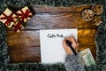 Hand writing on paper Gift list. Christmas decorations on wooden board. Christmas concept. Money on table for buying Christmas Royalty Free Stock Photo