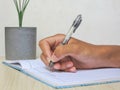 A hand writing with a pen on a notebook placed on a wooden patterned table, representing study, creativity, and productivity. Royalty Free Stock Photo