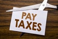 Hand writing text caption inspiration showing Pay Taxes. Business concept for Taxation Overtax Return Written on note, wooden back