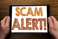 Hand writing text caption Scam Alert. Business concept for Fraud Warning Written on tablet laptop, wooden background with business Royalty Free Stock Photo