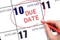 Hand writing text DUE DATE on calendar date January 10 and circling it. Payment due date Royalty Free Stock Photo