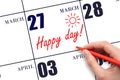 Hand writing the text HAPPY DAY and drawing the sun on the calendar date March 27
